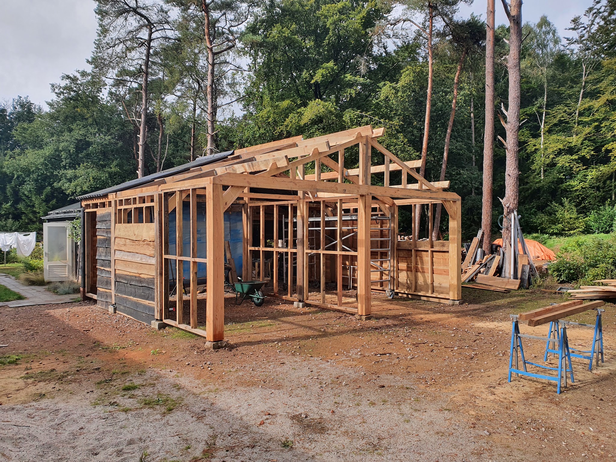 Houten kapschuur in aanbouw: het frame en de spanten staan, de wanden worden gesloten